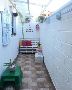 a small patio with white walls and plants on the bench, potted planters