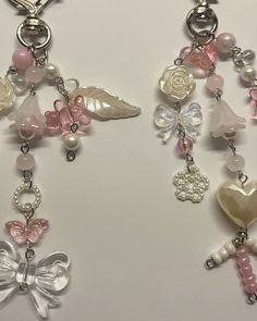 two necklaces with charms attached to them on a white surface, one has a heart and the other is a flower