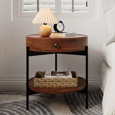 a small table with a lamp on it next to a bed in a white room