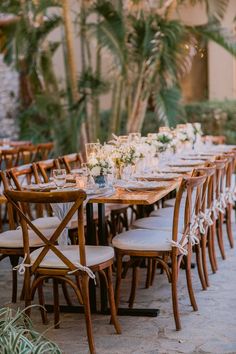 a long table with white flowers and greenery is set up for an outdoor wedding