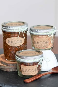 three jars filled with food sitting on top of a wooden table next to a spoon