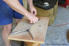 a man working on a piece of wood with a wrench and screwdriver