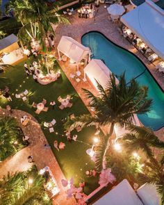 an aerial view of a pool and lawn area at night with lights on the ground