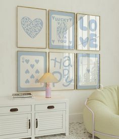 a living room with four framed pictures on the wall and a chair in front of it