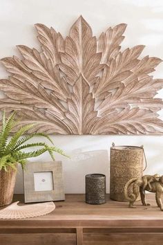 a wooden table topped with vases and plants next to a wall mounted art piece