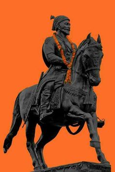 a statue of a man riding on the back of a horse in front of an orange sky