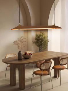 a dining table with four chairs and a bowl of fruit on it in front of an arched window