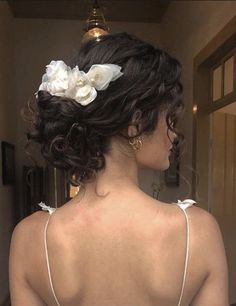 a woman with flowers in her hair is looking at herself in the mirror while wearing a wedding dress