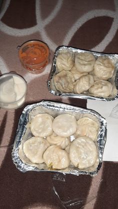 two pans filled with food sitting on top of a table next to an empty container