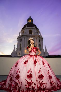 a woman in a red and white dress posing for the camera with a building in the background