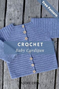 a blue knitted baby cardigan sitting on top of a wooden table with the words crochet baby cardigan written across it