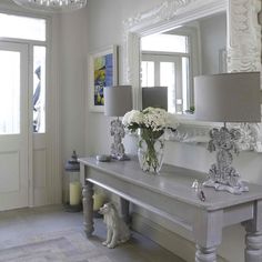 an image of a white room with flowers on the table and chandelier above it