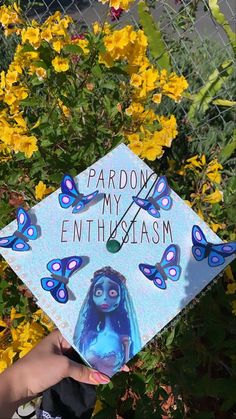 a person holding up a blue graduation cap with butterflies on it and the words, pardon my enthusiasm