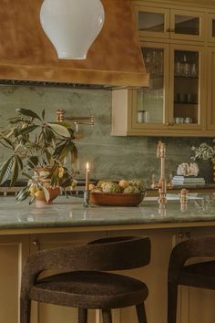 a kitchen counter with two stools next to it and a potted plant in the center