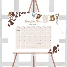 a baby shower calendar on a easel with clothes hanging from the clothes line,