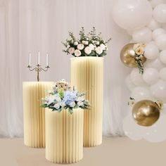 two tall yellow vases with flowers and candles on them are sitting in front of balloons