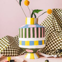 a colorful vase with flowers in it sitting on a table next to other decorative items