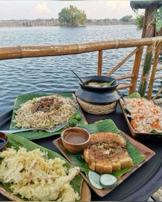 an assortment of food sitting on top of a table next to a body of water