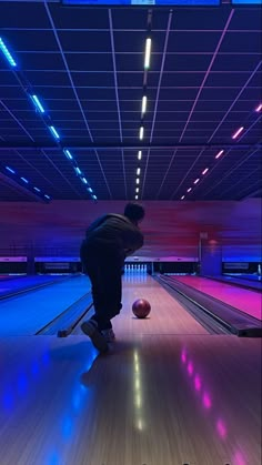 a man is bowling down a bowling alley with his foot on the ball in front of him