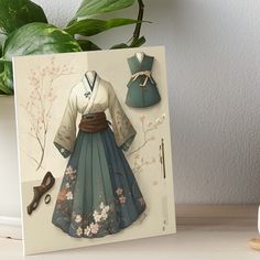 a card with an image of a woman's dress and shoes on display next to a potted plant