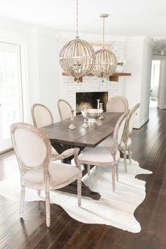 a dining room table with white chairs and a chandelier hanging from the ceiling