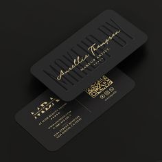 two black business cards with gold foil lettering on the front and back of each card