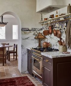 a kitchen with marble counter tops and brown cabinets, along with an archway leading to the dining room