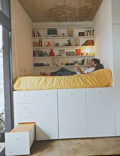 a man and woman laying on top of a bed in a room with bookshelves