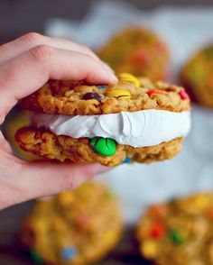 someone is holding a cookie sandwich with marshmallows and m & ms