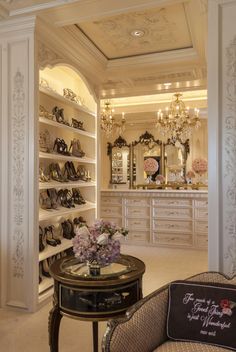 a room filled with lots of shoes and chandelier above a table in front of a mirror