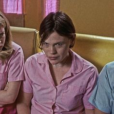 three women sitting on a couch with their hands folded and looking at something in front of them