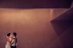 a bride and groom standing together in an empty room