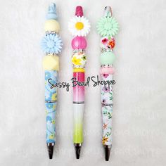 three pens are lined up next to each other on a white background with the words sassy bead shoppe