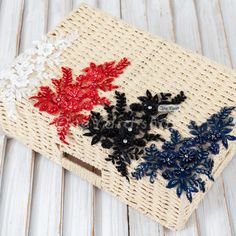 an embroidered piece of cloth with red, white and blue flowers sitting on top of it