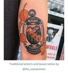 a tattoo with an image of a lantern and trees in the background, on someone's arm