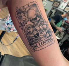 there is a tattoo on the arm of a person that has flowers and skulls on it