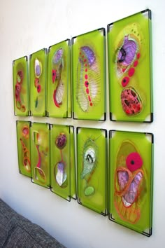 four green trays with different types of glass items mounted to the side of a wall