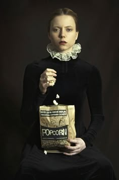 a woman holding a bag of popcorn in her hands