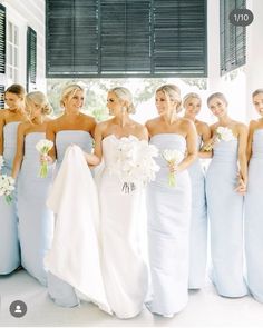 a group of women standing next to each other wearing dresses and holding bouquets in their hands