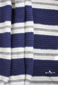 a blue and white crocheted blanket is laying on top of a bed sheet