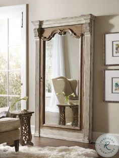 a large mirror sitting on top of a wooden floor next to a chair and window