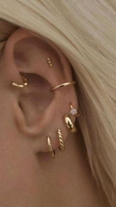 a woman with blonde hair wearing three different ear piercings