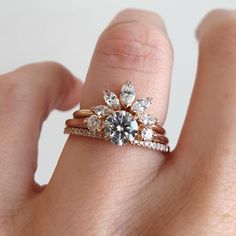 a woman's hand holding a ring with three stones on it and one diamond in the middle