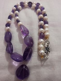 Amethyst Necklace Smooth AAA Tumble Beads With Center Tumble Gemstone 20 inch Necklace Stone : Natural Amethyst Fresh Water Pearl Shape :- Tumble Size :- 7x7-14x18mm 1. Weight :- 237 carat With Amethyst Tumble, 20 INCH Necklace Polish :- Handmade Purity :- 100% Natural Gemstone color - white blue It is known as the 'love stone' as the message it emits is the strong vibration of unconditional love, joy, warmth and healing. As quartz crystals are profound amplifiers of energy, it may help to kindl Purple Amethyst Gemstone Beads Pearl Necklace, Purple Amethyst Pearl Necklace With Gemstone Beads, Purple Necklace With Round Stone Beads, Purple Necklaces With Round Stone Beads, Purple Necklace With Round Stones, Polished Tumbled Bead Necklaces As Gifts, Amethyst Pearl Necklace With Gemstone Beads As Gift, Purple Gemstone Pearl Necklace Gift, Purple Jewelry With Polished Oval Beads