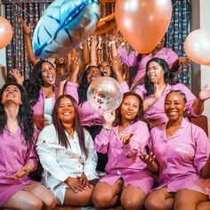 a group of women in pink outfits posing for a photo with balloons and streamers