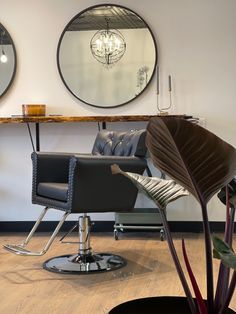 a chair and mirror in a room with wood flooring on one side and two circular mirrors on the other