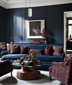 a living room with blue walls and plaid couches, coffee table, and art on the wall