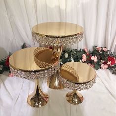 three tiered trays with gold colored dishes on them and flowers in the background