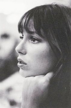 a black and white photo of a woman with her hand on her chin looking off into the distance