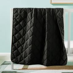 a baby crib with a black quilted blanket on top of the crib